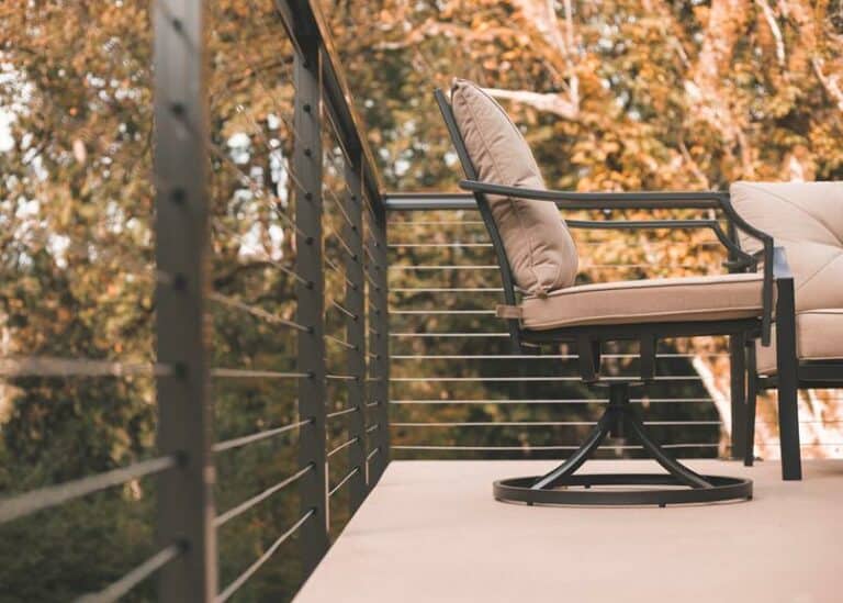 A chair on a deck with a view of trees.